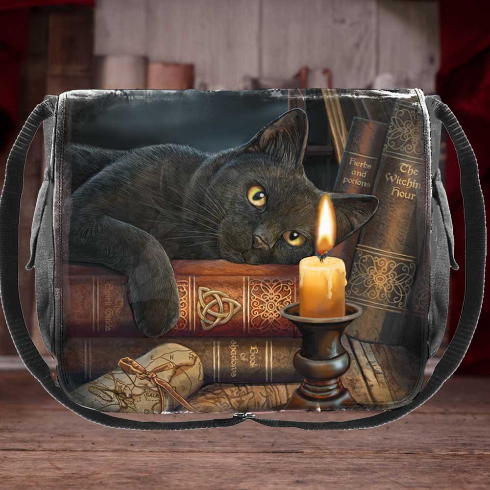 The printed image on a black messenger bag shows a black cat lounging on stacked books, with a lit candle nearby. The books are titled "The Spirit Guide," "Book of Shadows," "Herbs and Potions," and "The Witchin Hour."