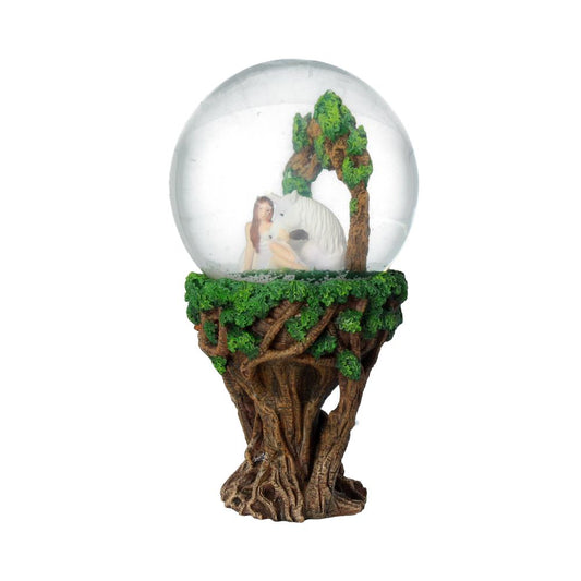 A snow globe depicts a woman and a wolf sitting under a tree. The globe sits atop a tree-trunk base.