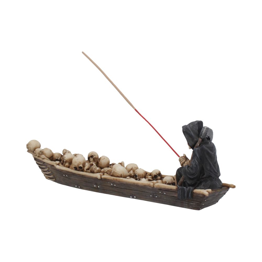 A grim reaper figurine sits in a skull-filled boat, holding a burning incense stick; the scene is isolated on a white background.
