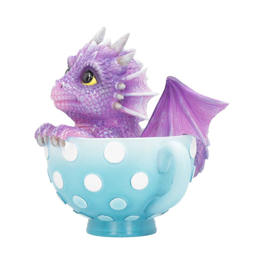 A small, purple dragon sits inside a blue polka-dotted teacup, gazing outward. Its wings are folded and horns are prominent. The scene is whimsical and colorful.