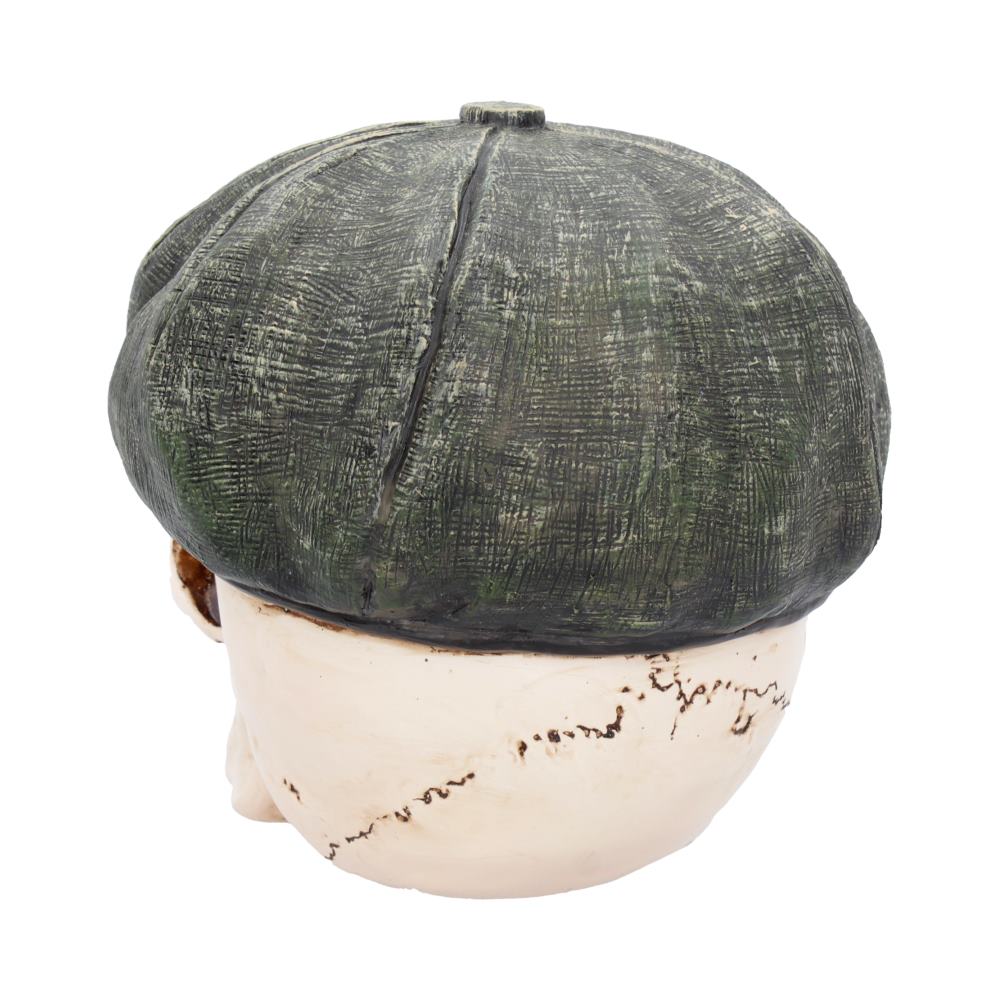 An artificial head wearing a textured, dark green, flat cap. The head has visible hand-painted details and is set against a plain white background.