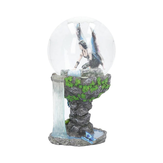 A fairy figurine sits inside a glass sphere atop a sculpted rock waterfall base.