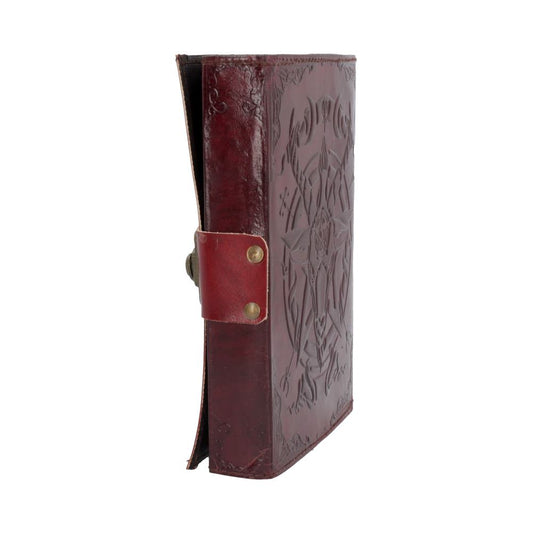 A closed, brown leather-bound book with embossed designs sits upright, featuring a decorative strap with metal buttons as a fastening mechanism. The background is plain white.