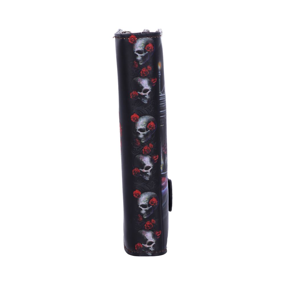 A black wallet stands upright; its surface displays a repeated pattern of skulls and red roses flanking a dimly lit scene.