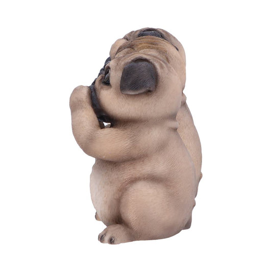A pug figurine sits upright while holding its paw up to its mouth as if it is biting it. The background is plain white.