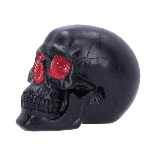 A black skull, with cracked surface details, features red, glittery eye sockets, resting on a plain white background.