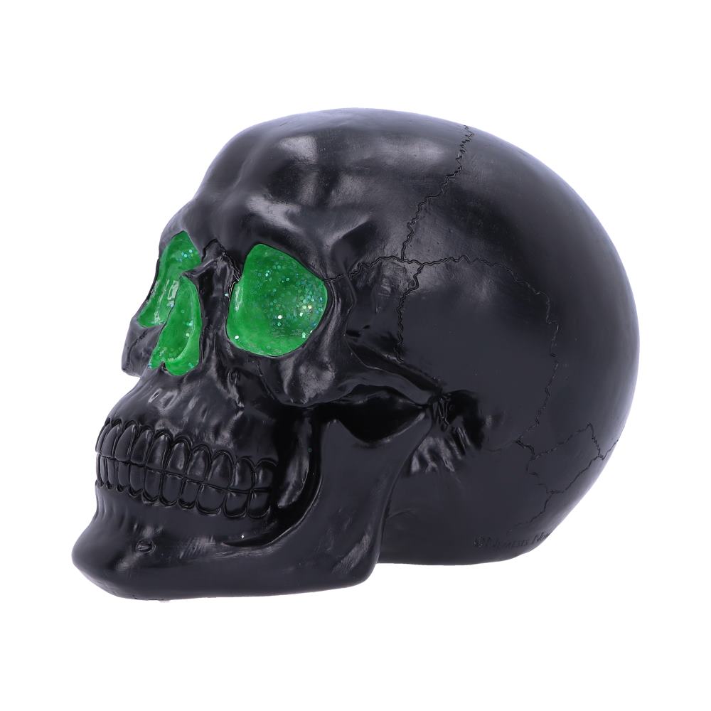 A black skull with vibrant green eye sockets rests against a plain white background, showcasing cracks and textured details on its surface.
