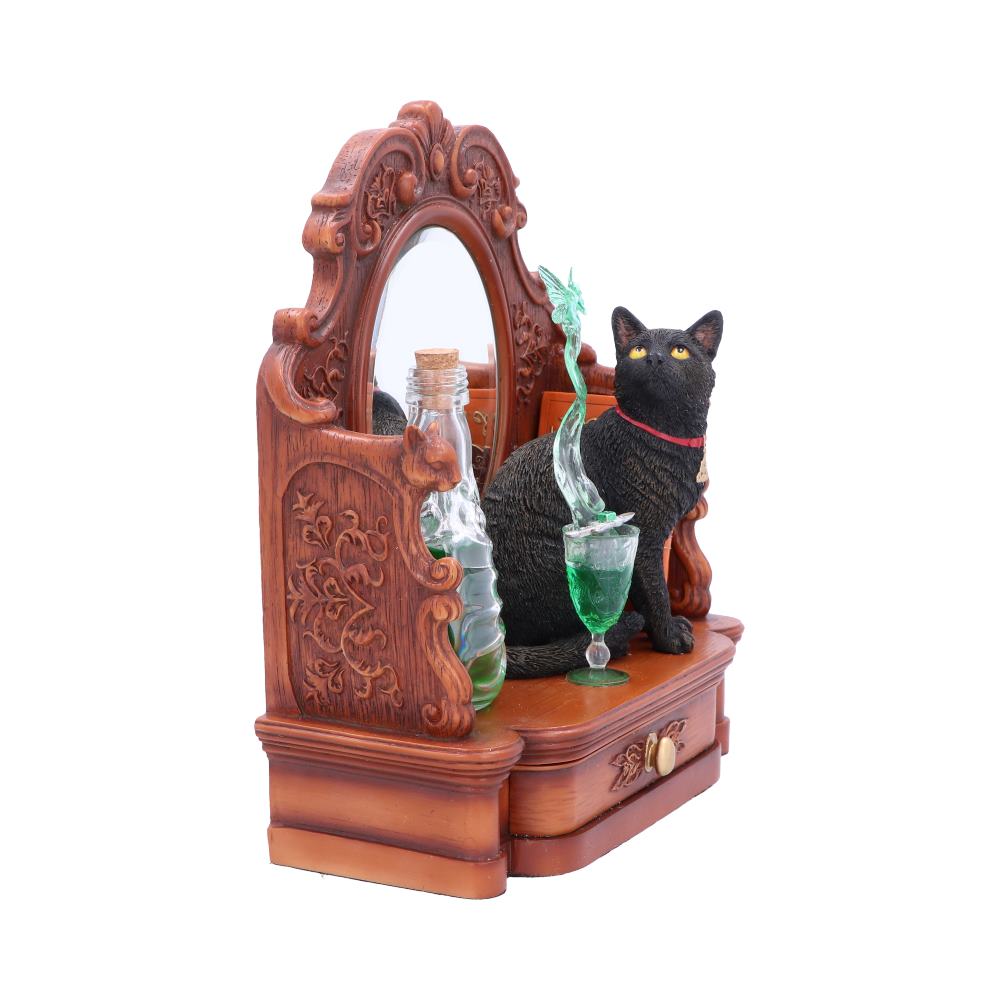 A black cat figurine sits on an ornate wooden dresser with a mirror. A green liquid-filled glass and bottle accompany it, adding a mystical atmosphere.