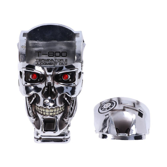 A metallic skull with red eyes and an open jaw stands upright; next to it lies a detached piece. Text on the skull reads: "T-800 TERMINATOR 2 JUDGMENT DAY." White background.