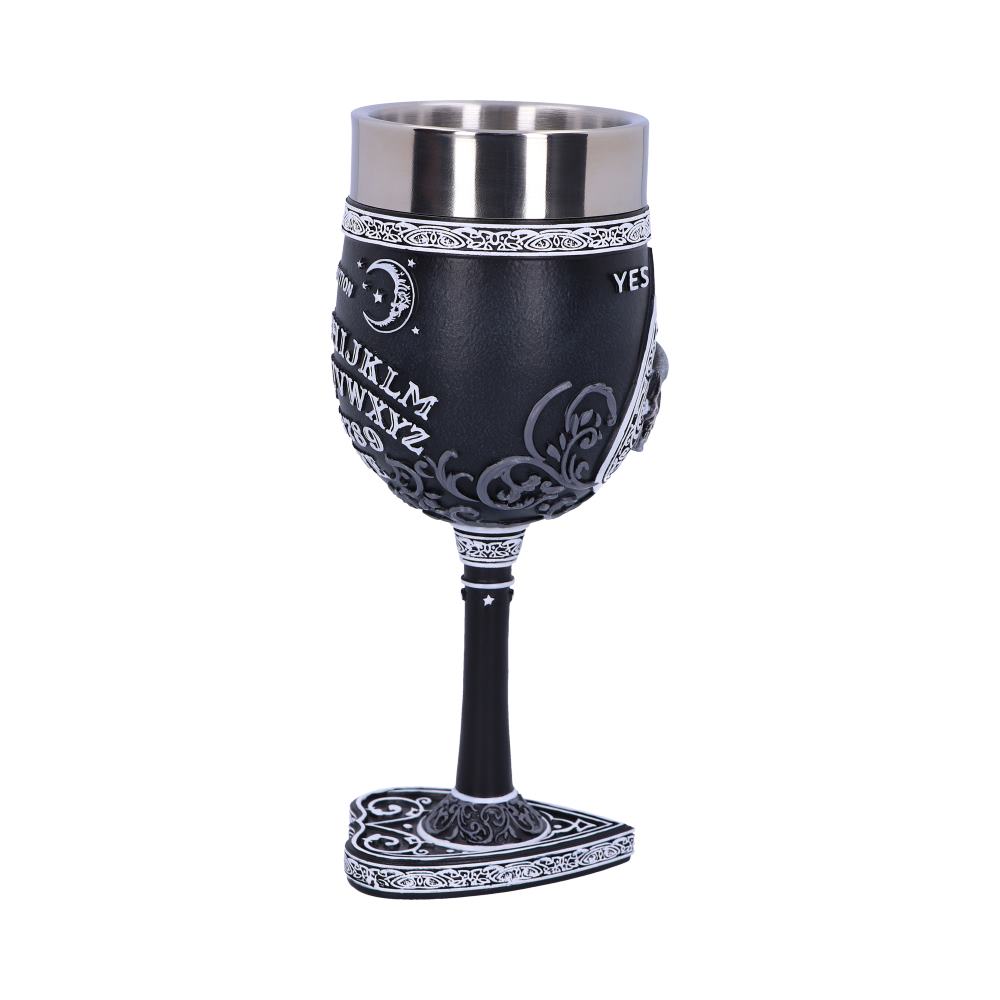 A decorative goblet stands on a white surface. The cup displays a Ouija board design including letters "IJKLMNOPQRSTUVWXYZ" and "YES" along with stars and moon.