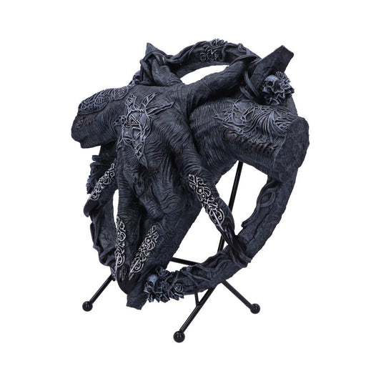 A dark, intricately carved circular sculpture featuring organic, vine-like patterns sits on a three-legged stand. Decorative skull motifs accentuate its mystical, gothic appearance.