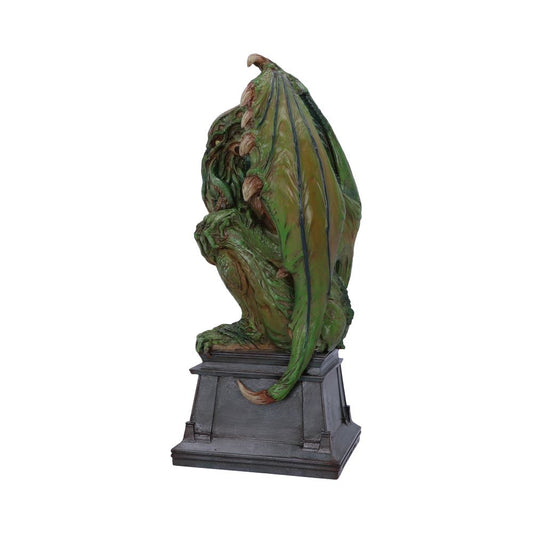 Cthulhu statuette perches, resting on a stone-colored pedestal. It is mottled green, with tentacles near its face and large, green-brown wings. The background is plain white.