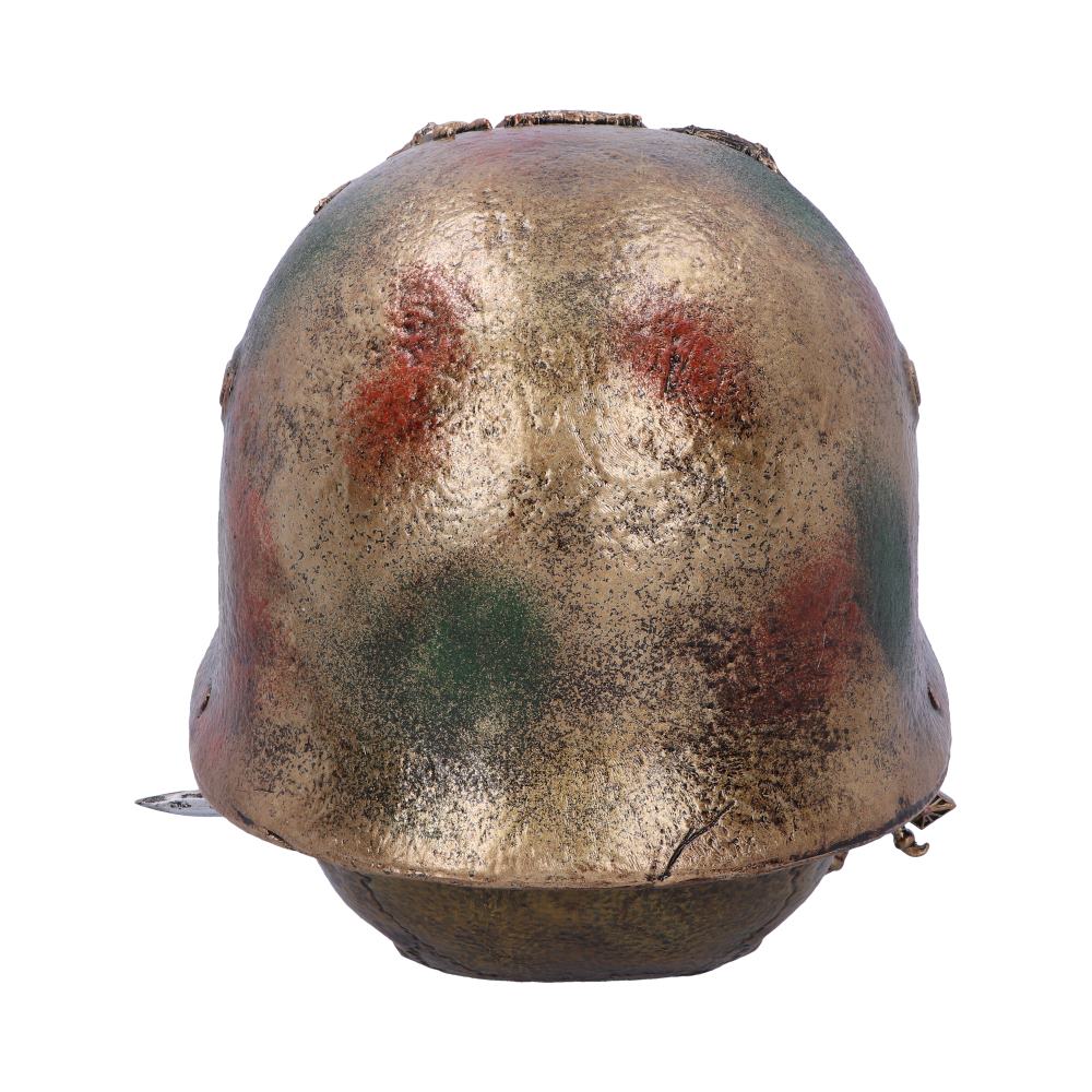 A weathered metal helmet features a camouflaged pattern with green and red patches, sitting alone against a plain white backdrop, suggesting a vintage or military theme.