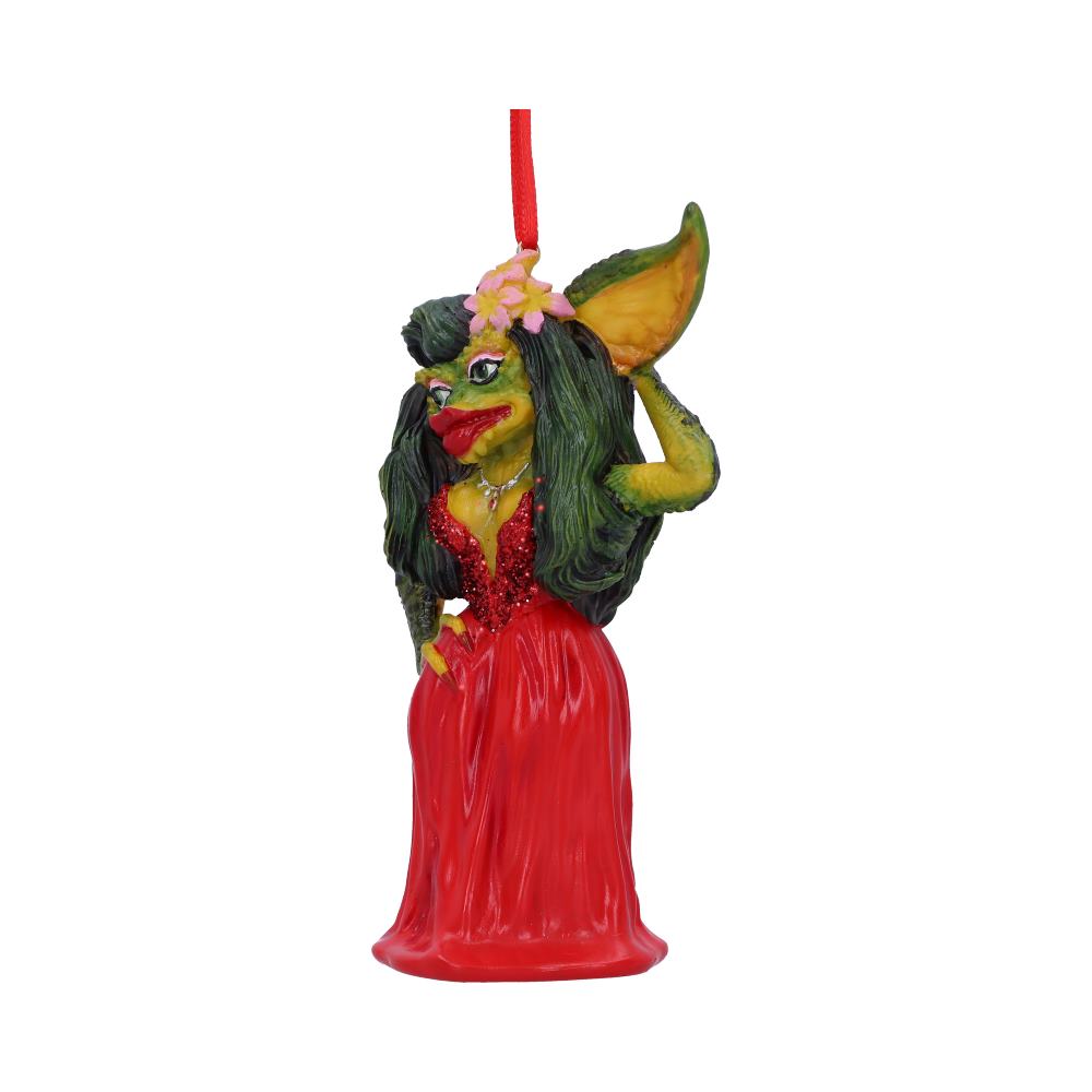 A green creature figurine, wearing a red dress and adorned with pink flowers, strikes a pose. It hangs from a red string, set against a plain white background.