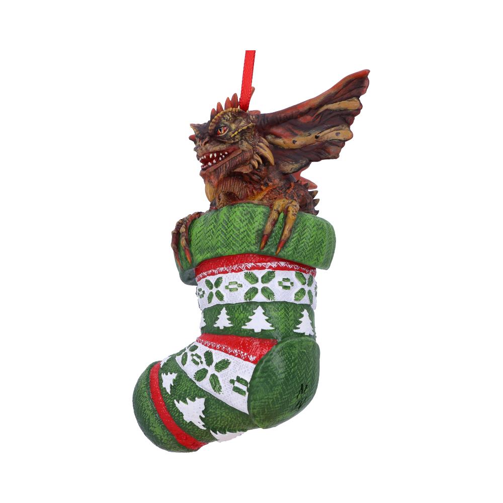 A dragon emerges from a green Christmas stocking decorated with red trim and white holiday patterns, hanging by a red ribbon against a plain background.