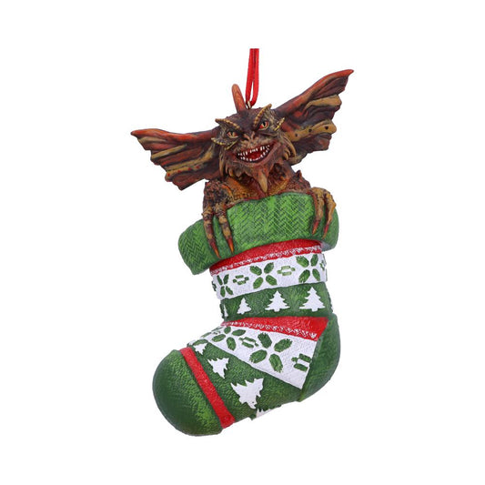 A creature with large ears and sharp teeth emerges from a Christmas stocking. The green stocking features red and white patterns with holiday-themed designs and hangs from a red loop.