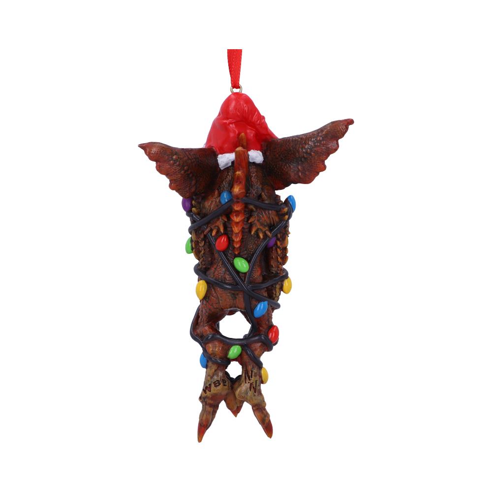 A winged creature ornament is wrapped in colorful Christmas lights, hanging by a red string. It features a Santa hat and has "GREMLINS" written on its feet, against a plain white background.