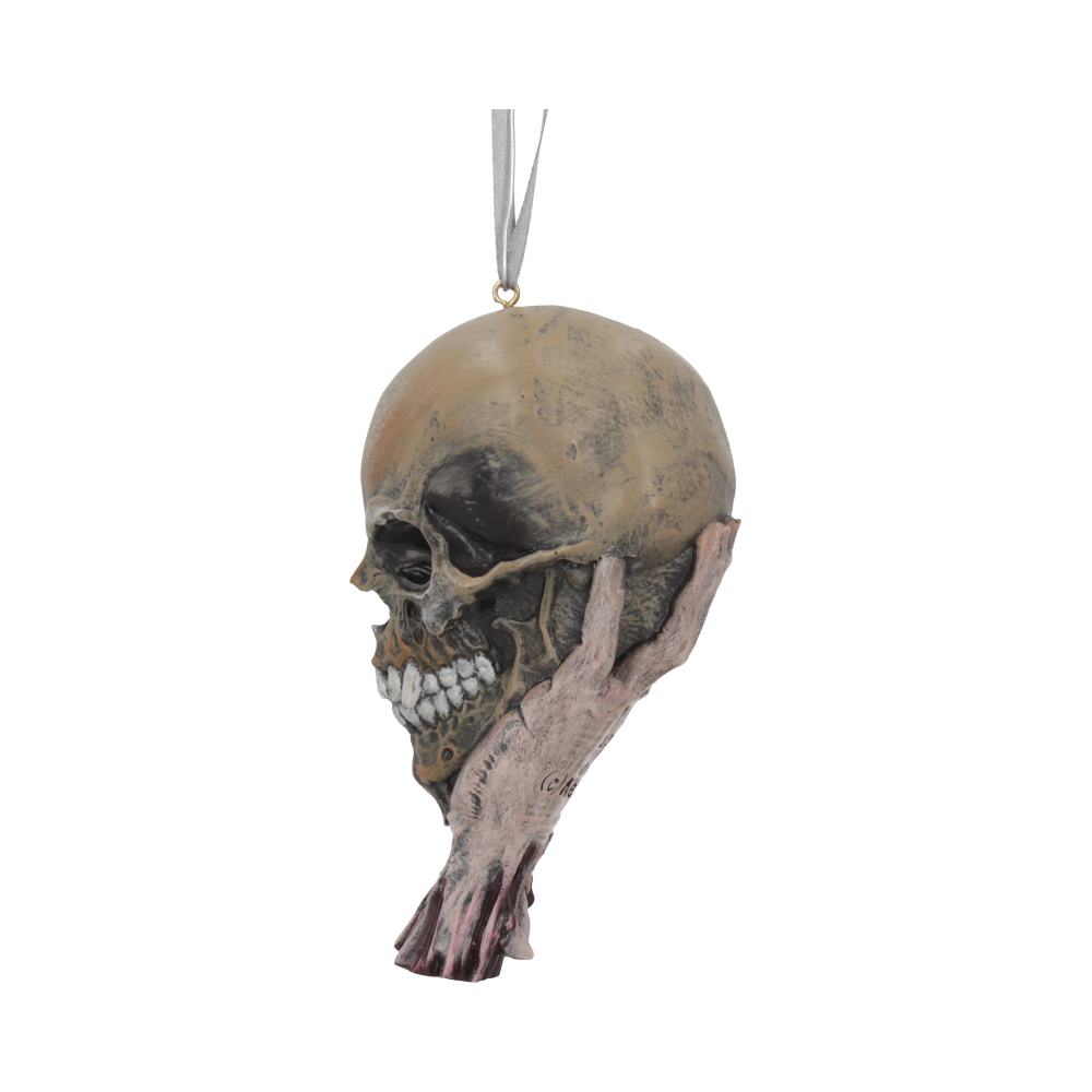 Weathered human skull ornament cradled by a gnarled skeletal hand, showing exposed teeth and dark eye sockets, suspended from a gray ribbon against a plain white background.