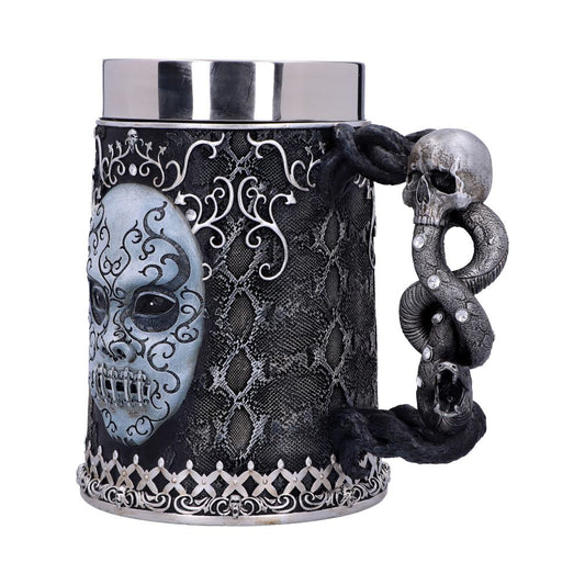 A large, ornate mug features an embossed skull face with intricate swirling designs. The handle resembles a coiled snake intertwined with a skull. The background is a decorative, textured pattern.