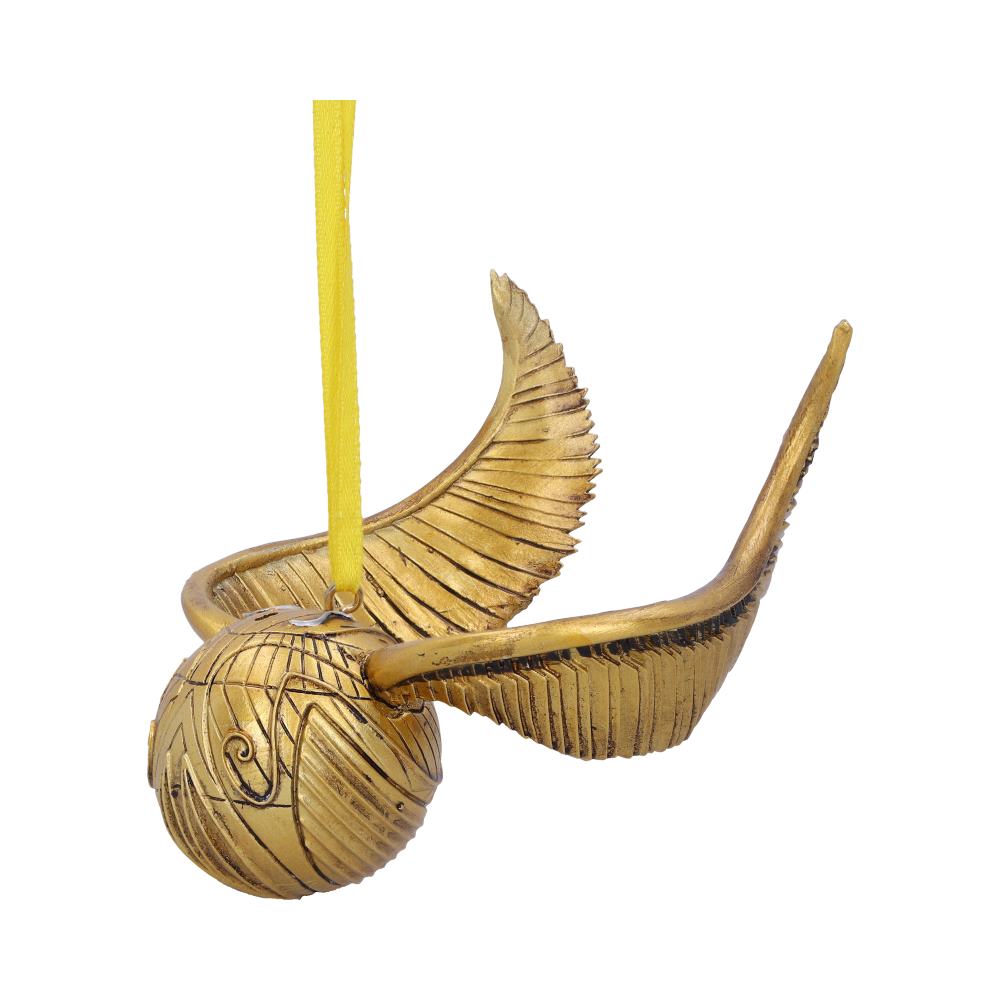 A gold spherical ornament with engraved designs and large, curved wings hangs suspended by a yellow ribbon, set against a plain white background.