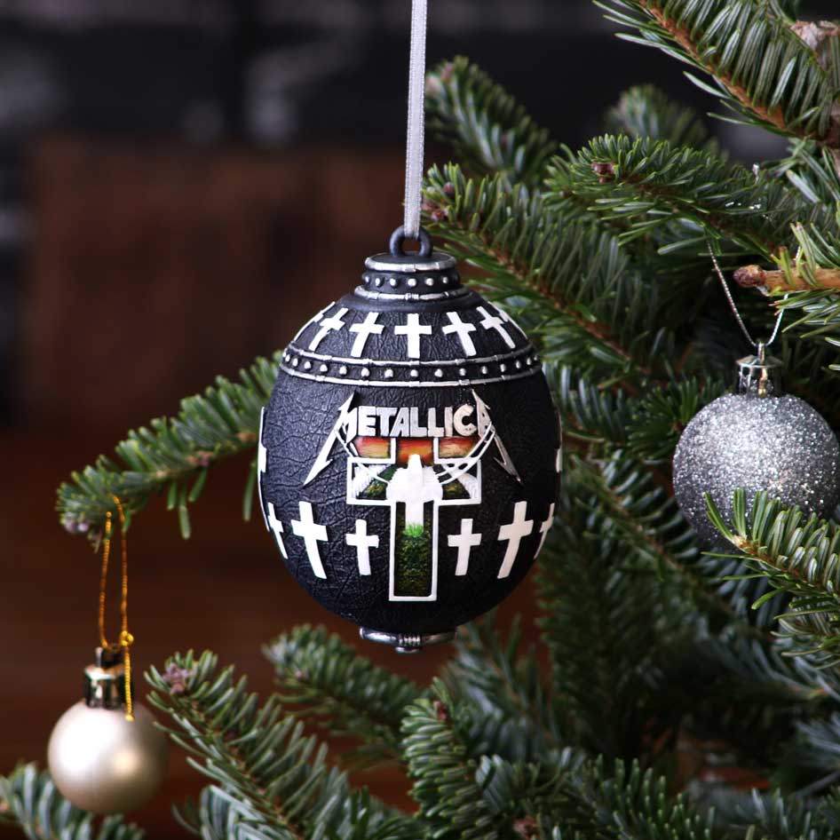 Black spherical ornament decorated with white crosses and the word "METALLICA" hangs from a ribbon on a green Christmas tree branch, surrounded by silver and pearl baubles.