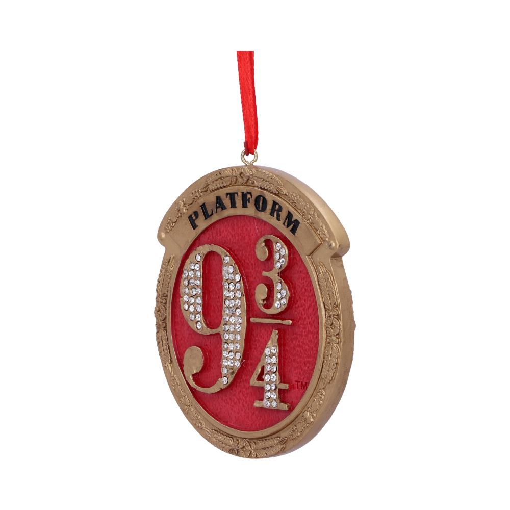 An ornate, oval ornament displays "PLATFORM 9 3/4" in gold with rhinestones on a red background, hanging from a red ribbon. The outer frame is gold-toned with decorative patterns.