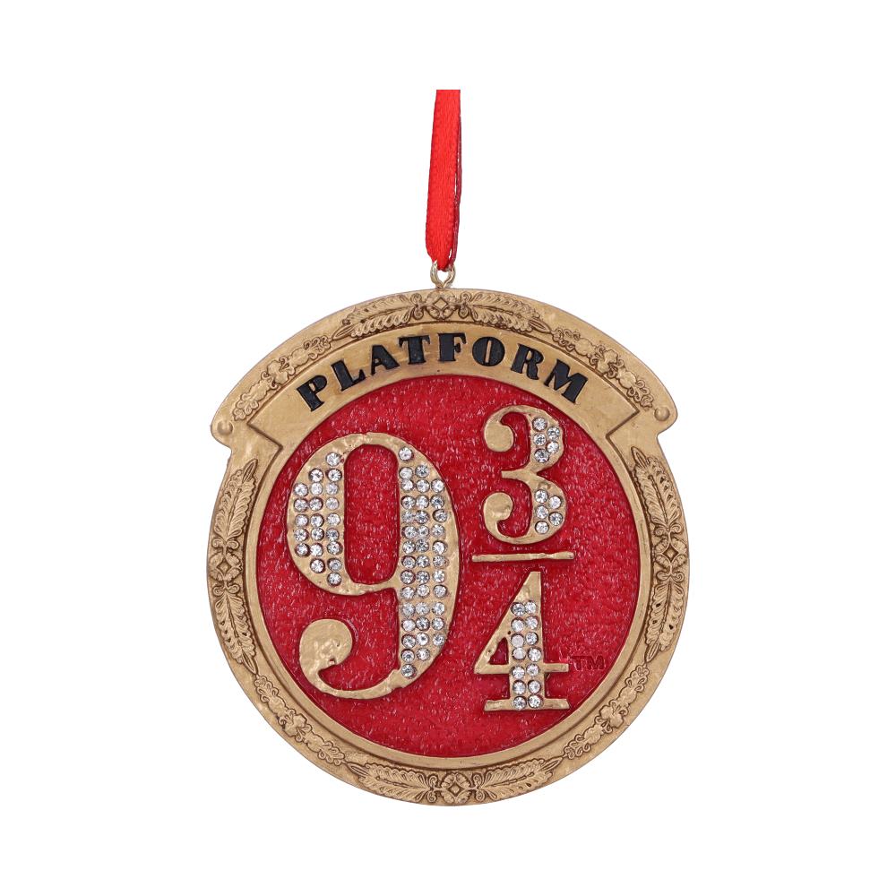 A round ornament features the stylized text "PLATFORM 9 3/4" with rhinestones on "9," set against a red background. It's edged in gold, hanging from a red ribbon.