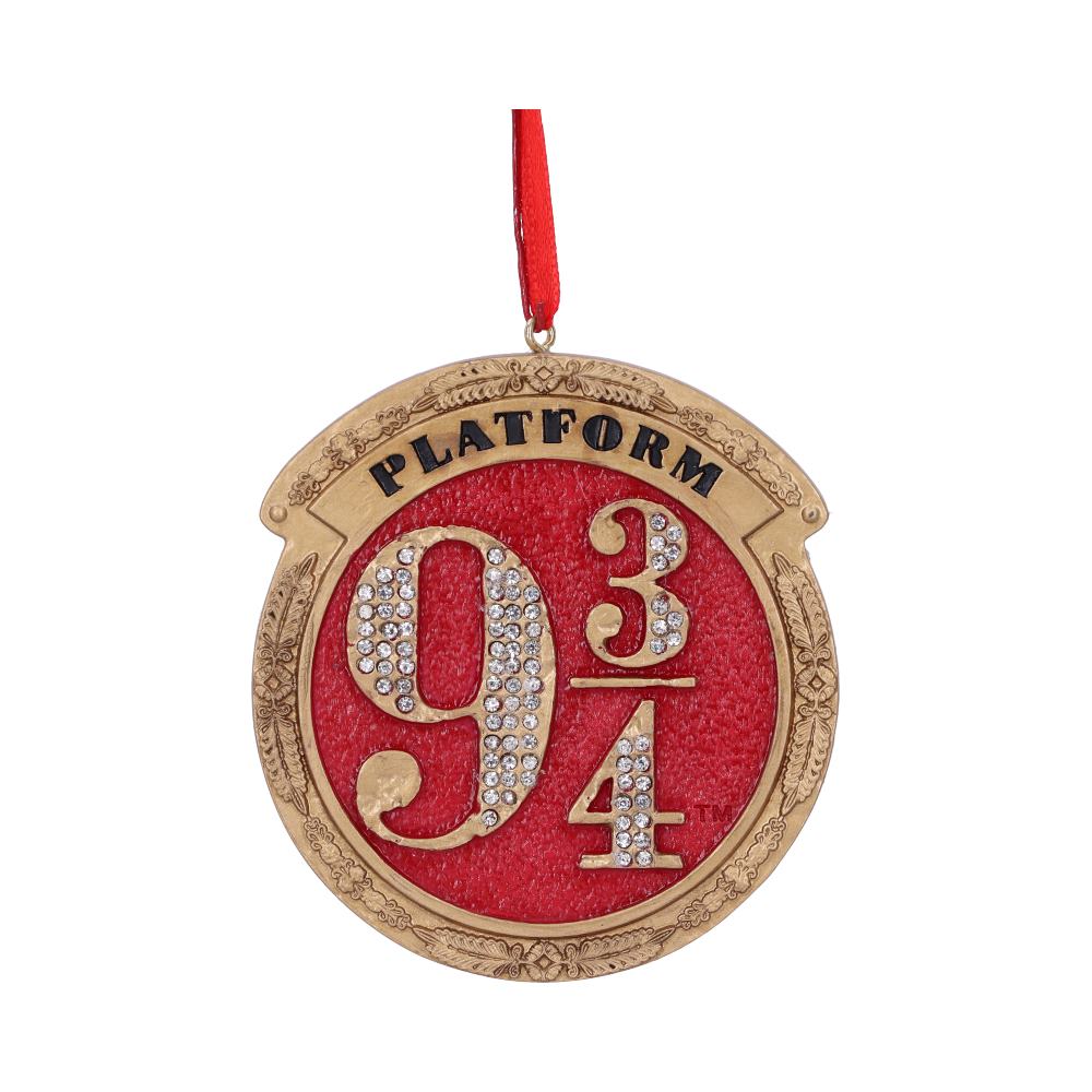 A circular ornament features "Platform 9 3/4" text in gold, with embellished numbers on a red background, surrounded by ornate gold edging, and suspended by a red ribbon.