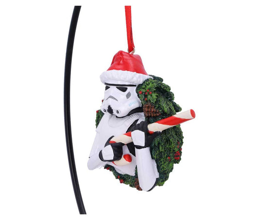 A Stormtrooper wearing a Santa hat holds a candy cane, nestled within a green Christmas wreath, hanging by a red ribbon against a plain white background.