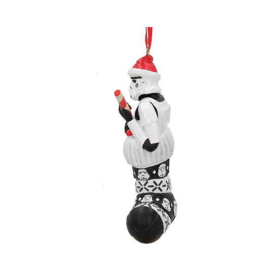 A Stormtrooper figurine, wearing a Santa hat, holds a red-and-white candy cane while sitting in a black-and-white stocking with Stormtrooper designs, hanging from a red ribbon.