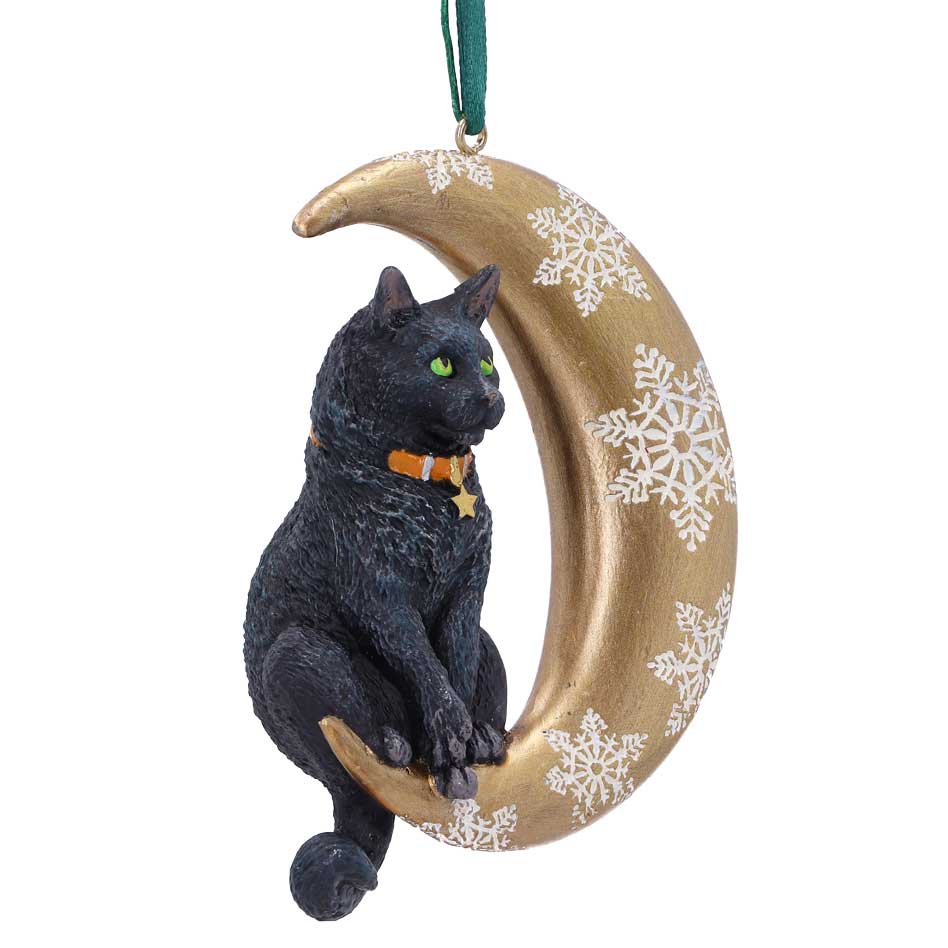 Black cat ornament perches on a gold crescent moon adorned with white snowflakes, with an orange collar and star, hanging from a green ribbon against a white background.