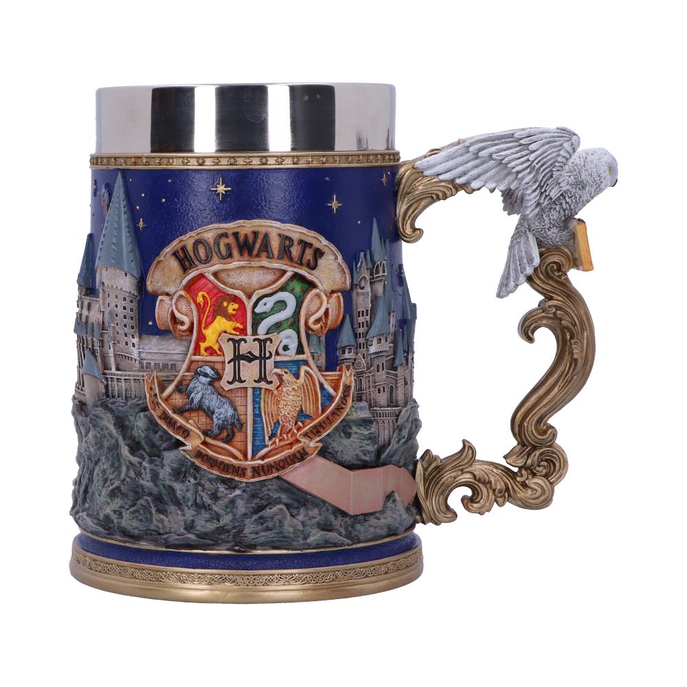 A decorative mug features a detailed Hogwarts crest with lion, snake, badger, and eagle on a relief of Hogwarts castle. A sculpted phoenix forms the ornate handle. Text: "HOGWARTS," "DRACO DORMIENS NUNQUAM TITILLANDUS."