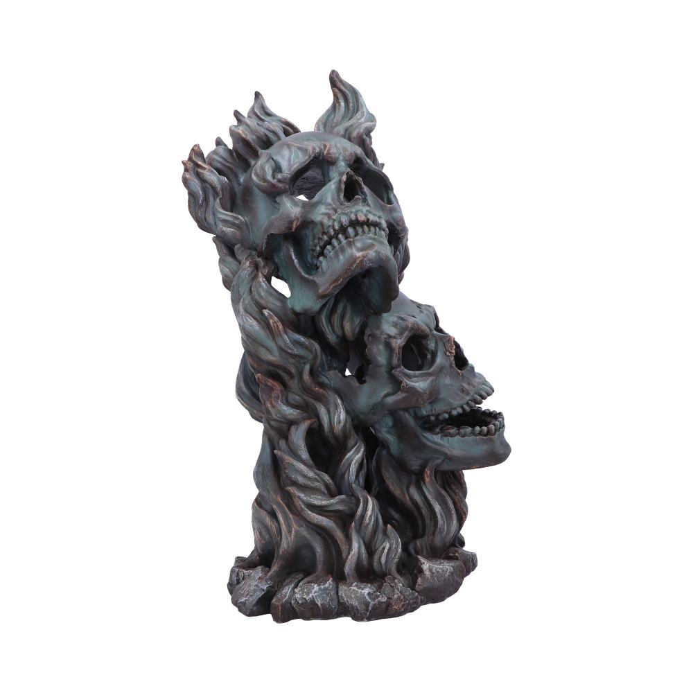 A sculpture of two intertwined skulls emerges from a base resembling swirling flames, with intricate detailing in a dark, metallic finish against a plain, white background.