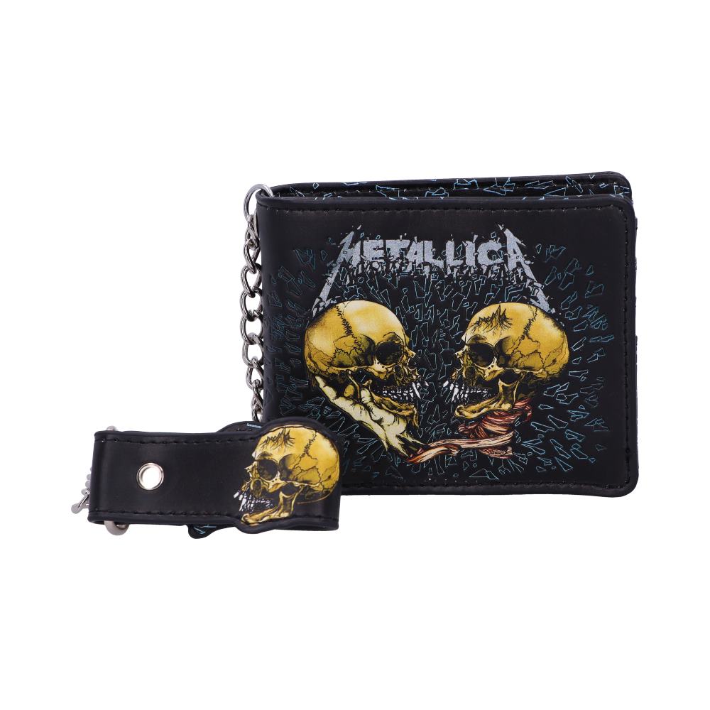 A black wallet featuring two yellow skulls facing each other with "METALLICA" text above. The wallet has an attached chain and a snap button strap with a similar skull design, set against a white background.