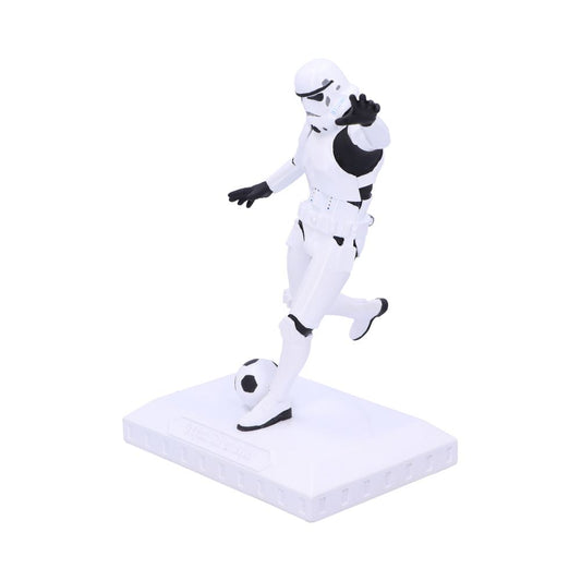 A stormtrooper figurine kicks a soccer ball while positioned on a rectangular base. The scene is set against a plain white background.