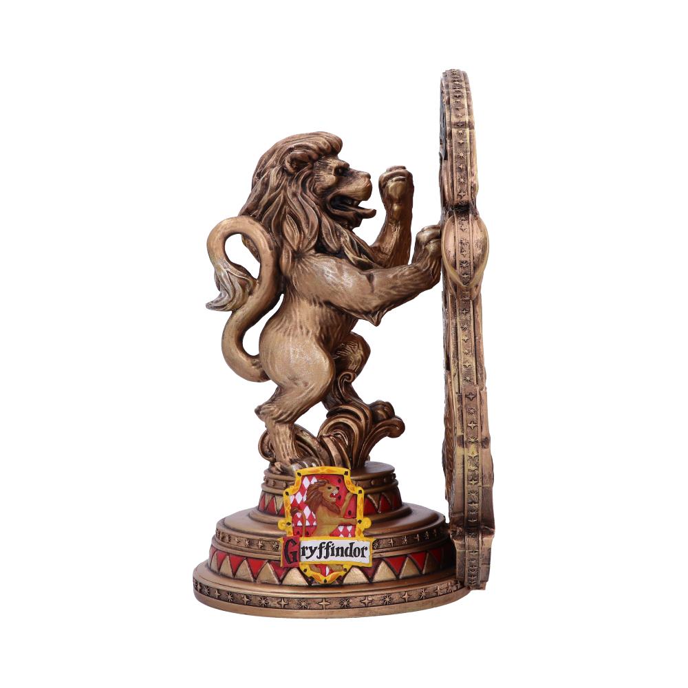 A lion figurine stands upright, with one paw on a wheel-like design. The base features a Gryffindor emblem with a lion and the text "Gryffindor" beneath it.