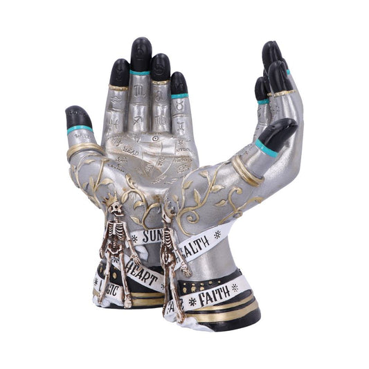 Two silver-colored hands are open, palms-up, side-by-side. They are decorated with mystical symbols, as well as text reading "*SUN*, *HEART*, *MAGIC*, HEALTH, *FAITH*" and tiny skeleton figures. The context is a white background.