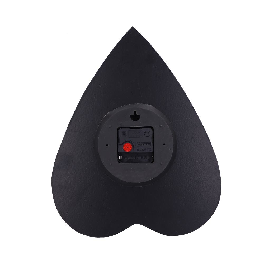 A black, spade-shaped clock face, featuring a battery compartment with visible text: "QUARTZ" and symbols, positioned centrally on a plain white background.