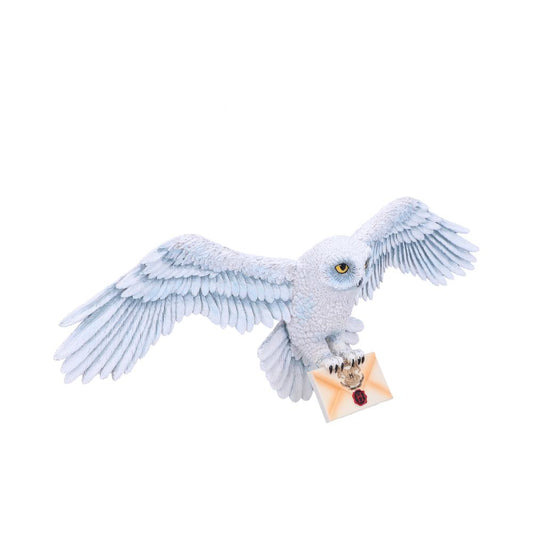 A snowy owl with outstretched wings carries a sealed envelope in its talons, flying against a plain white background.