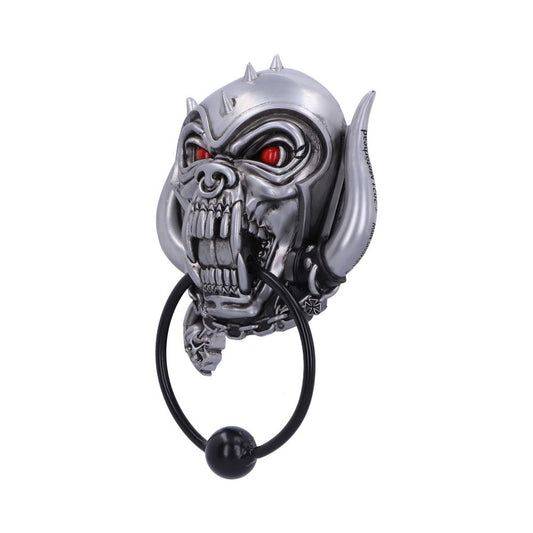 A metallic, menacing dog-like face with spikes and red eyes holds a black ring in its mouth, resembling a door knocker. It appears isolated against a white background.