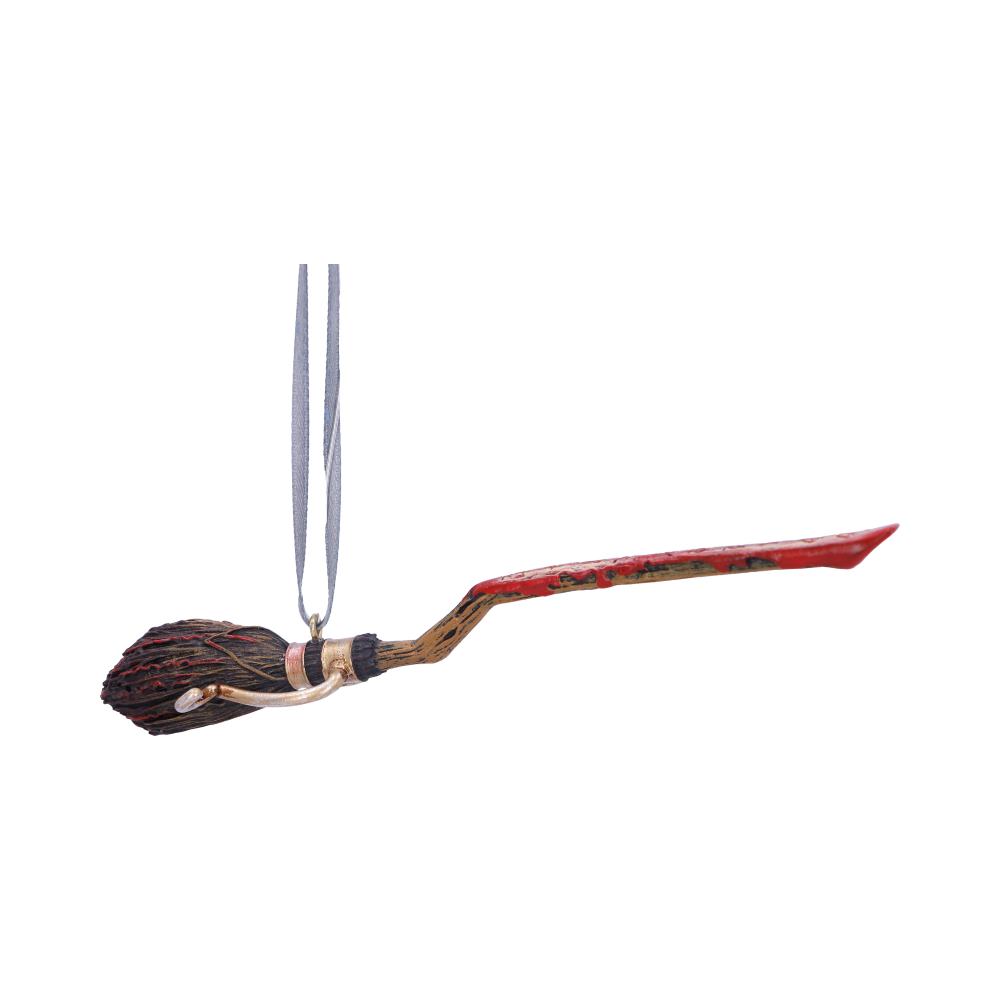 A decorative broomstick ornament hangs suspended by a silver ribbon. The broomstick has a red handle with intricate designs, resembling a whimsical, magical theme against a plain white background.