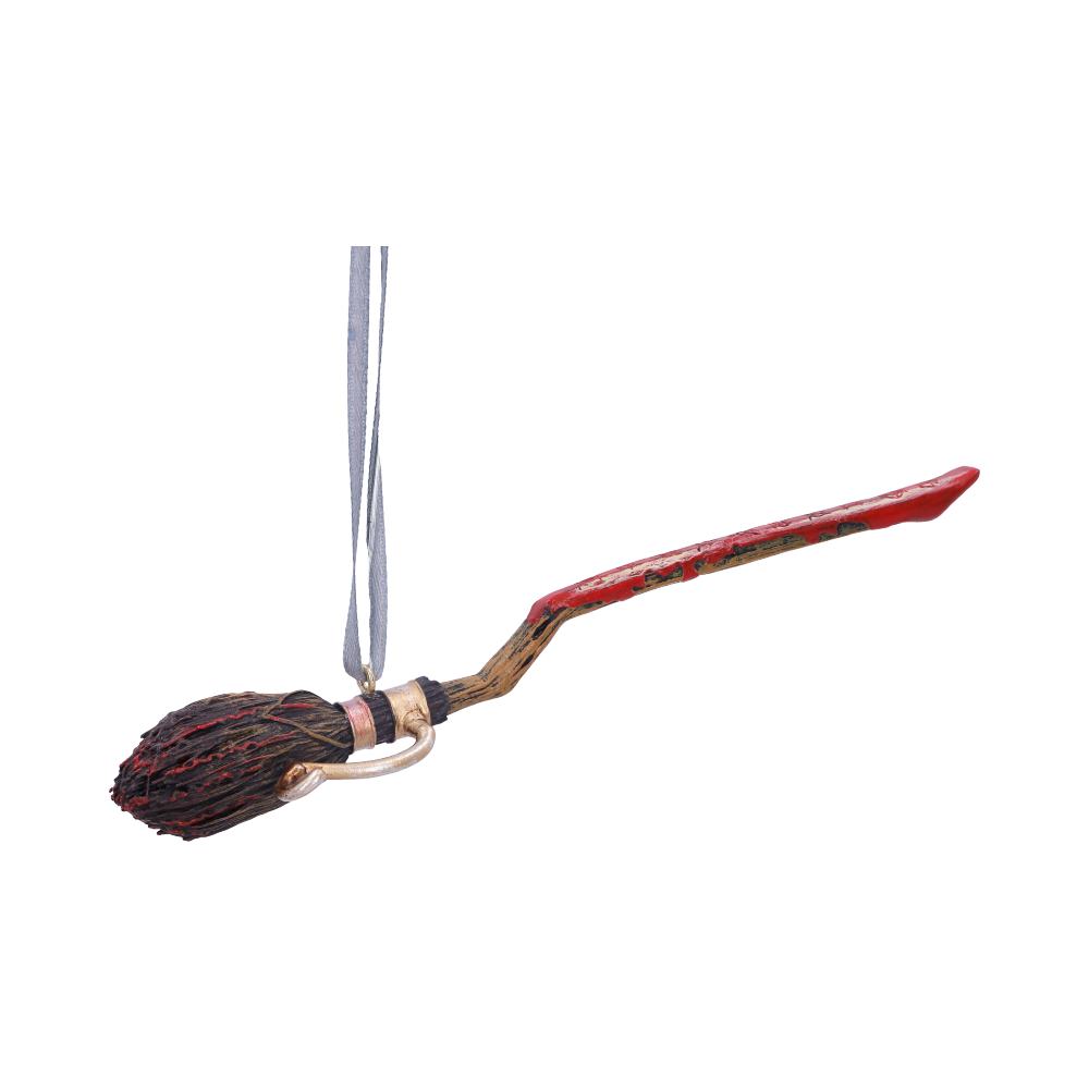 A decorative broomstick ornament hangs from a thin ribbon. It features a textured, red handle and an intricately detailed brush, suggesting a whimsical or magical theme, against a plain background.