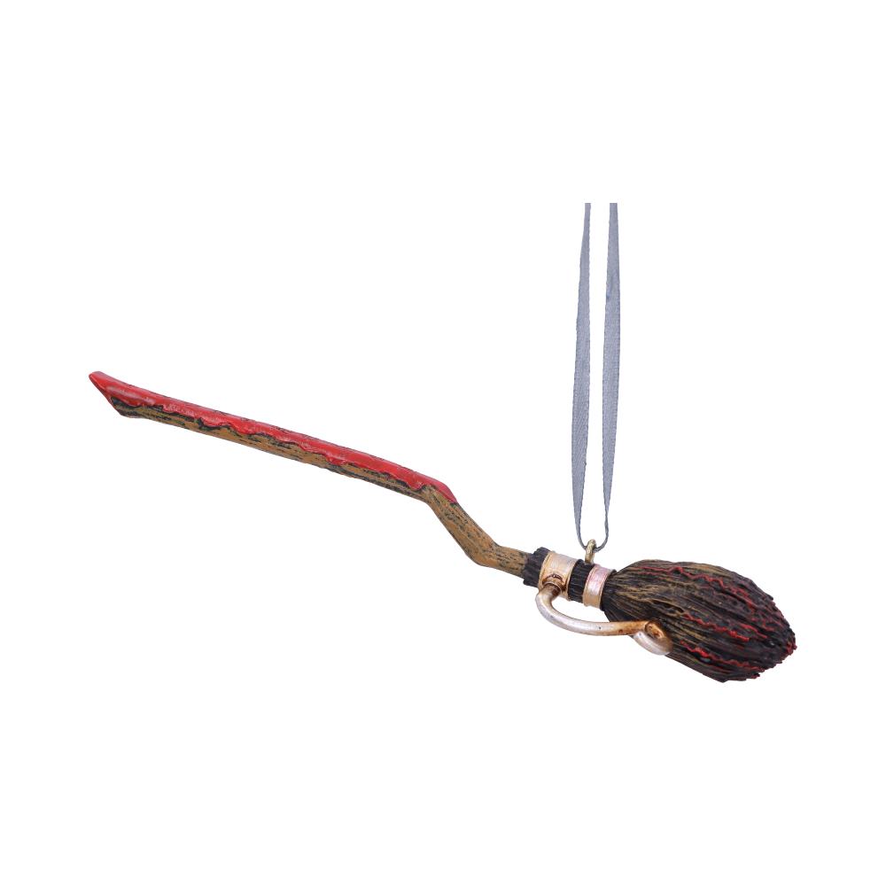 A small, red-handled broomstick ornament with bristles is hanging from a gray ribbon, positioned against a plain white background.