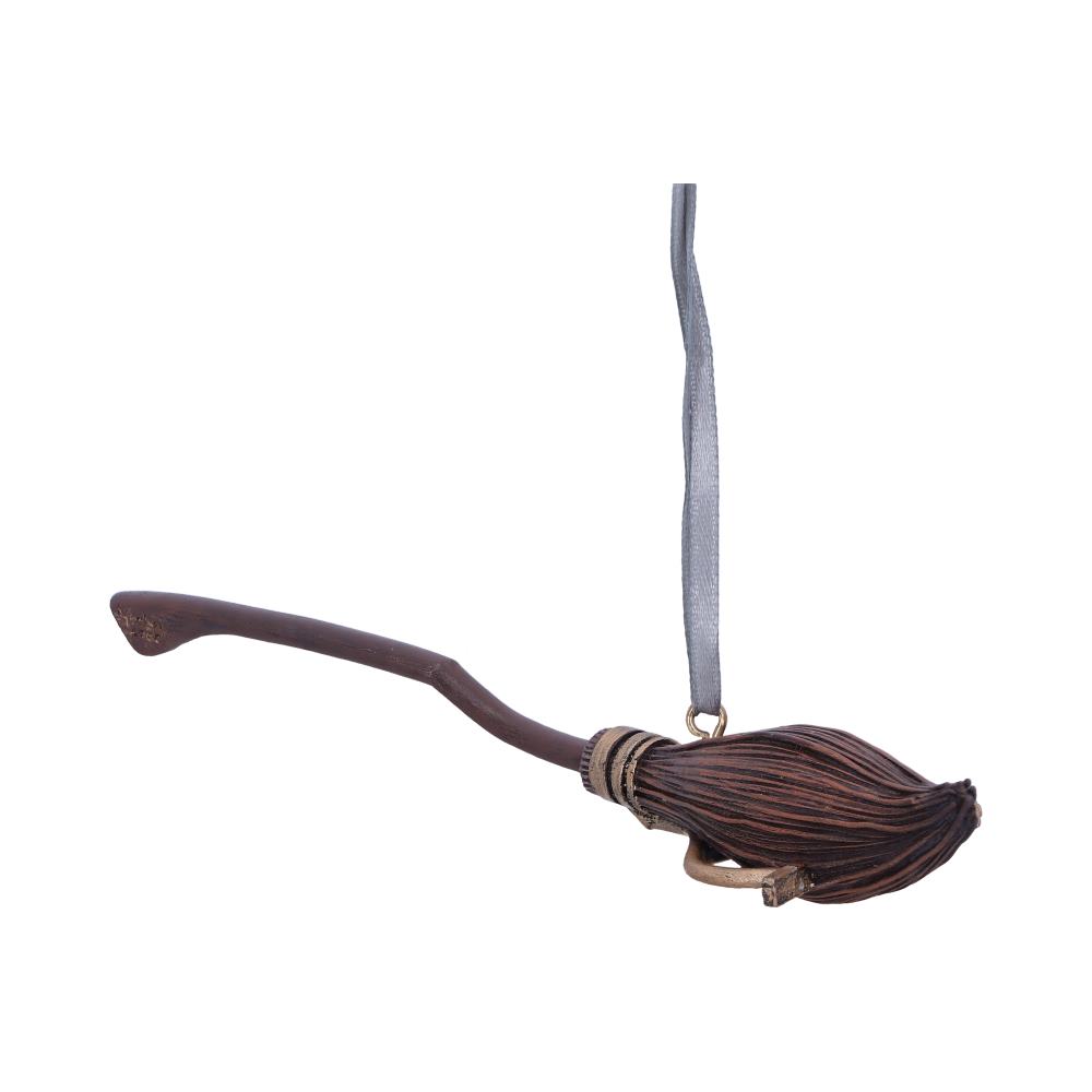 A small, intricately detailed broomstick ornament hangs from a gray ribbon, set against a plain white background.