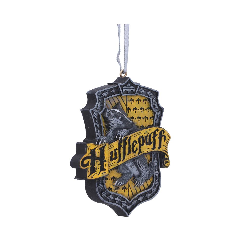 A Hufflepuff crest ornament hangs on a ribbon, featuring a badger and the word "Hufflepuff" on a yellow and black shield. It is isolated on a white background.