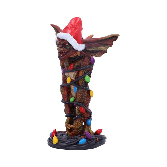 A creature figurine is wrapped in colorful Christmas lights, wearing a red Santa hat. It stands on a coiled wire, set against a plain white background.