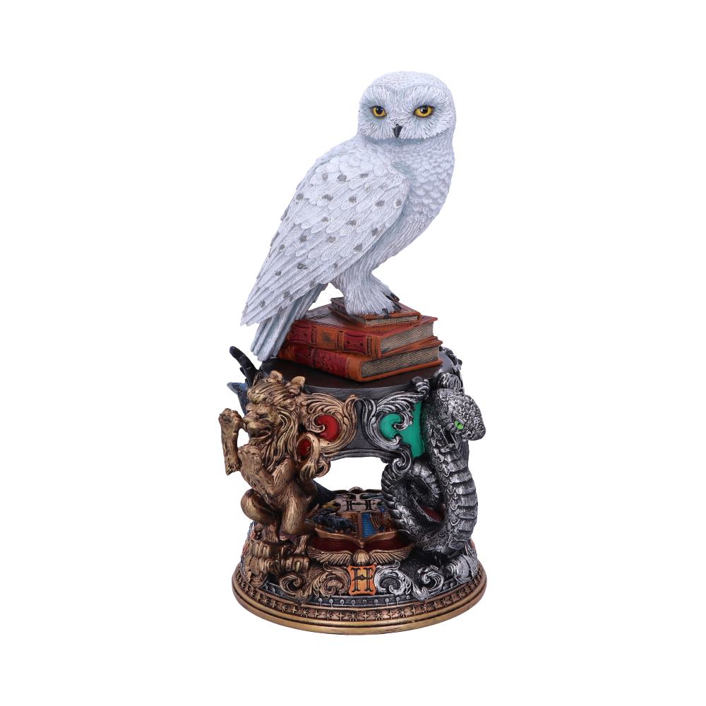 A white owl figurine perched on stacked books sits atop a decorative base featuring a lion and serpent in a detailed, ornate style.
