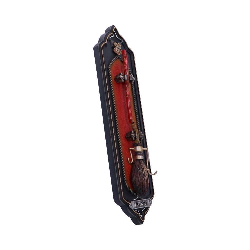 Broomstick mounted on a decorative red and black plaque, secured with metal hooks. The plaque features a tag labeled "FIREBOLT," alluding to a fantasy theme.