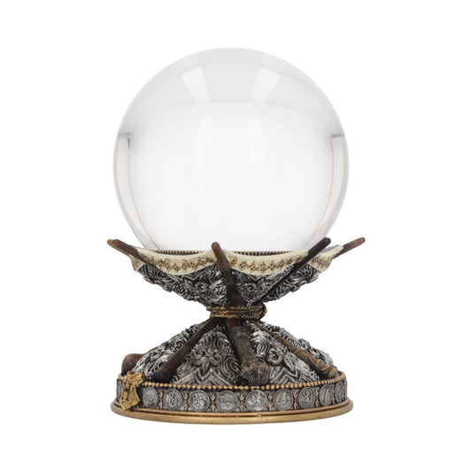 A clear crystal ball rests on an ornate metal stand with decorative floral patterns and circular motifs, set against a plain white background.