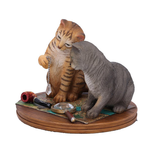 Two cat figurines sit on a wooden base with a map, magnifying glass, and pipe. One cat holds a chain with a crystal.